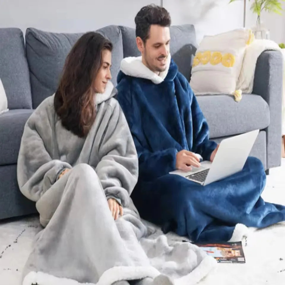 Couple bien au chaud dans la couverture à capuche Cozya sur le canapé